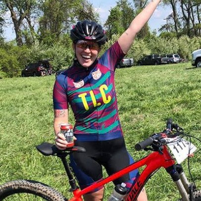 Lauren raises her hand in the air after a mountain bike race.