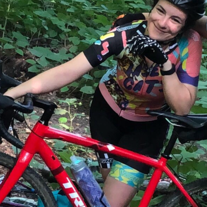 woman leans on a cyclocross bike in the woods